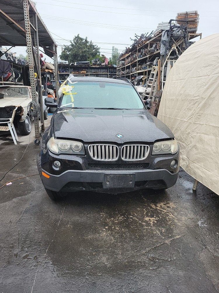 BMW X3 in the Universal Auto Dismantling yard with used parts on the racks behind it
